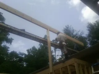 Carpenter setting a ridge beam over a new addition frame — Ice Dam Removal by Roofing Brothers in Hustonville