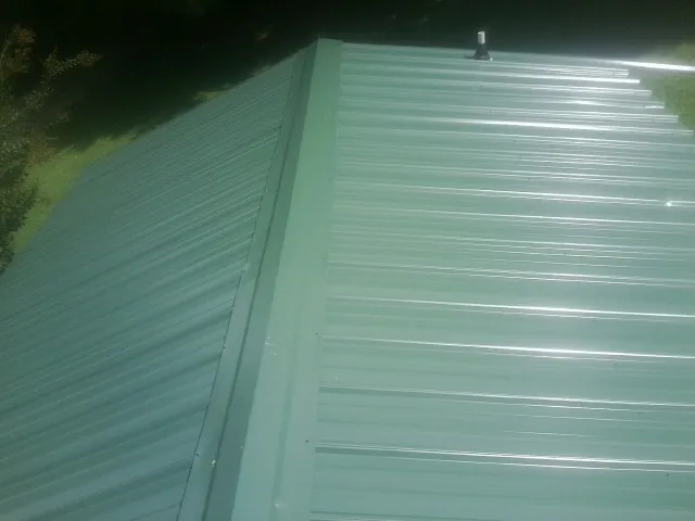 New green metal panels meeting at the ridge of a roof — Flat Roof Repair work by our crew in Hustonville