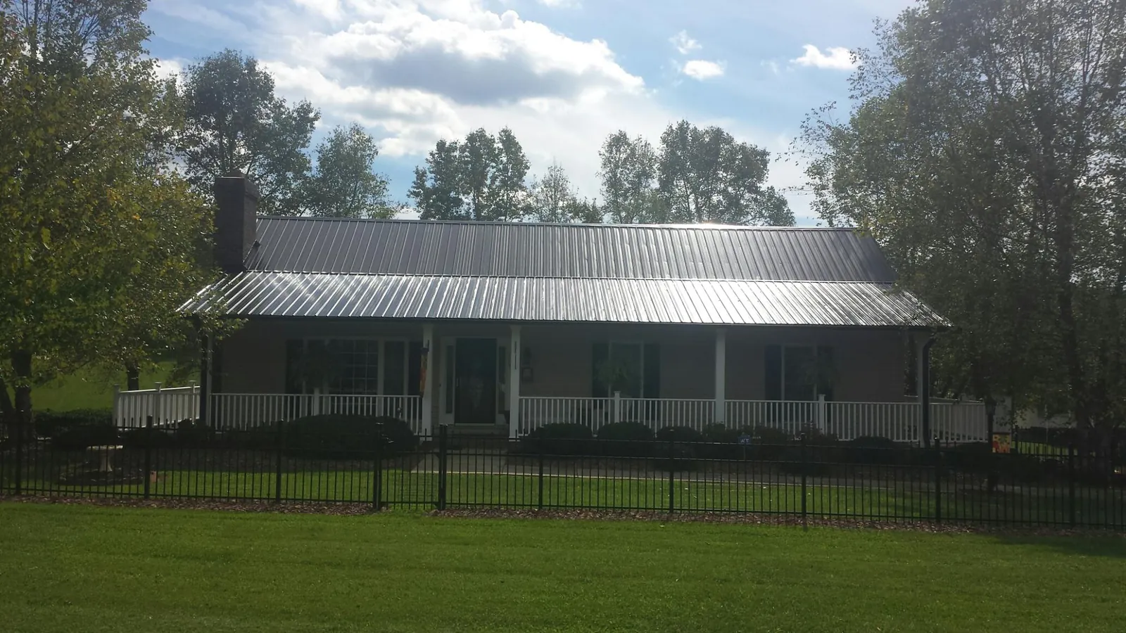 Gray metal roof on a brick ranch with a full width front porch — Gutter Guard Installation work by our crew in Hustonville