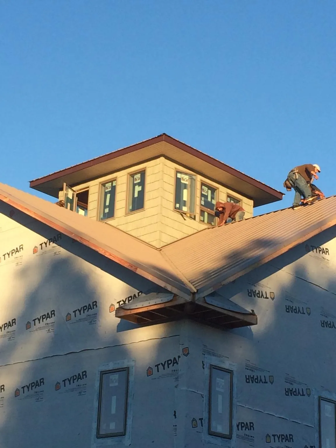 Roofers working around a rooftop cupola on a new metal roof at sunset — Roof Waterproofing in Hustonville by Roofing Brothers